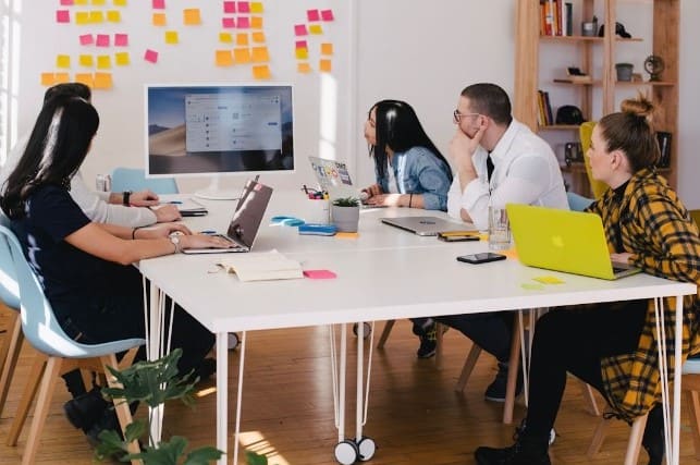 Alt text: A team in an office discussing purchase intent during a meeting 
